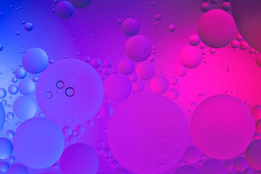 Su yüzeyi renk arkaplanına yağ damlaları düşer. mavi ve pembe daireler 