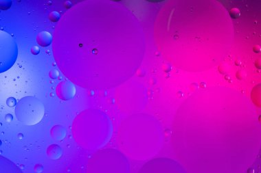 Su yüzeyi renk arkaplanına yağ damlaları düşer. mavi ve pembe daireler 