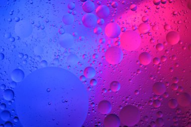 Su yüzeyi renk arkaplanına yağ damlaları düşer. mavi ve pembe daireler 