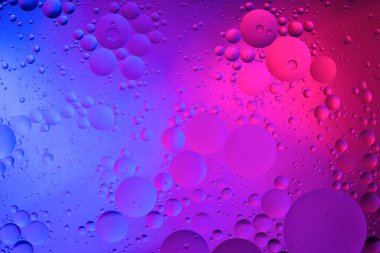 Su yüzeyi renk arkaplanına yağ damlaları düşer. mavi ve pembe daireler 