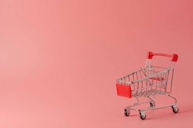 Alışveriş konsepti: Pembe arka planda kırmızı alışveriş arabası ve fotokopi alanı