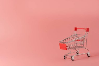 Alışveriş konsepti: Pembe arka planda kırmızı alışveriş arabası ve fotokopi alanı