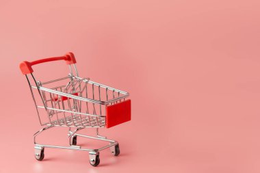 Alışveriş konsepti: Pembe arka planda kırmızı alışveriş arabası ve fotokopi alanı