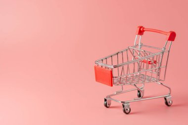 Alışveriş konsepti: Pembe arka planda kırmızı alışveriş arabası ve fotokopi alanı