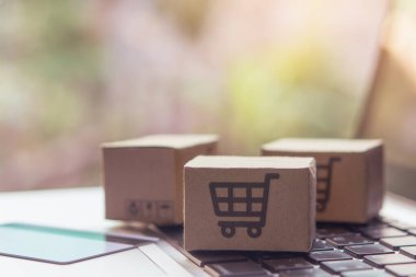 İnternetten alışveriş, kağıt kutular ya da klavyede alışveriş arabası logosu olan bir paket. İnternet üzerinden alışveriş hizmeti sunuyor..