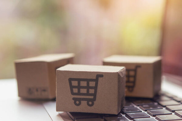 Интернет-магазины - бумажные коробки или посылка с логотипом корзины покупок на клавиатуре ноутбука. Торговые услуги в Интернете и предлагает доставку на дом
.