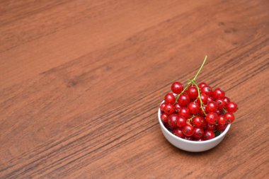 Kırmızı kuş üzümü ve kiraz ahşap bir masa üzerinde beyaz plaka