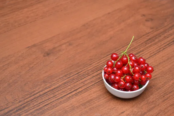 # Red currant and cherry in the white plate on a wood table # — Stok Foto