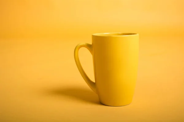 Empty yellow cup on yellow background. Yellow mug empty blank for coffee or tea — Stock Photo, Image