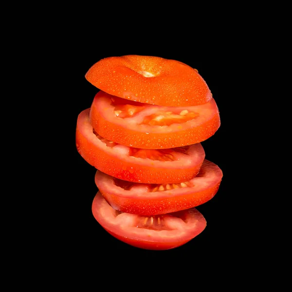 Fliegende Tomaten. geschnittene rote Tomate isoliert auf schwarzem Hintergrund. — Stockfoto