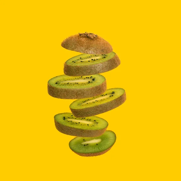 Flying kiwi. Sliced kiwi isolated on yellow background. Levity fruit — Stock Photo, Image