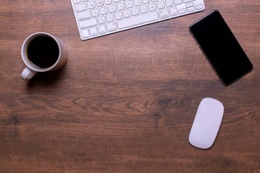 Bir klavye, bir cep telefonu, beyaz bir fincan çay ve bir ahşap bir bilgisayar fare