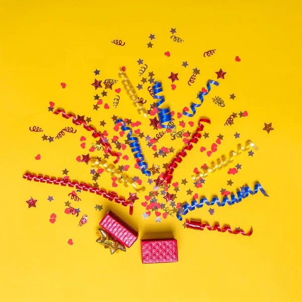 Conceito criativo com decoração festiva no fundo amarelo. Explosão de confete . — Fotografia de Stock