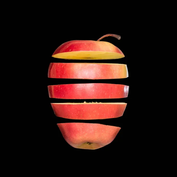 空とぶリンゴ。黒の背景に分離された赤いリンゴをスライスしました。空に浮かぶ軽さフルーツ. — ストック写真