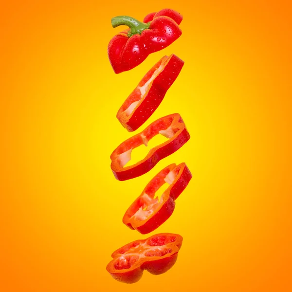 Creatief concept met vliegende oranje paprika. Zwevende paprika gesneden op een oranje achtergrond. — Stockfoto
