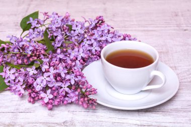 Kahve ya da çay ve bir buket leylak ahşap arka plan üzerinde beyaz Kupası.