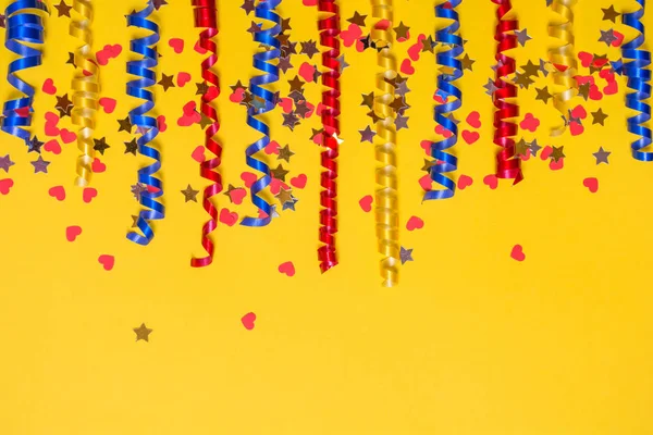 Fronteira de fitas festivas coloridas e confete em um fundo amarelo. Cenário do presente . — Fotografia de Stock