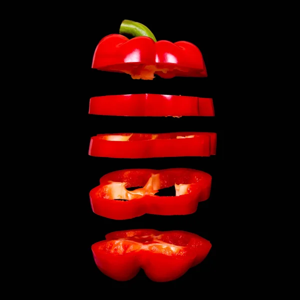 Creatief concept met vliegende rode paprika. Gesneden zwevende peper geïsoleerd. Lichtzinnigheid capsicum — Stockfoto