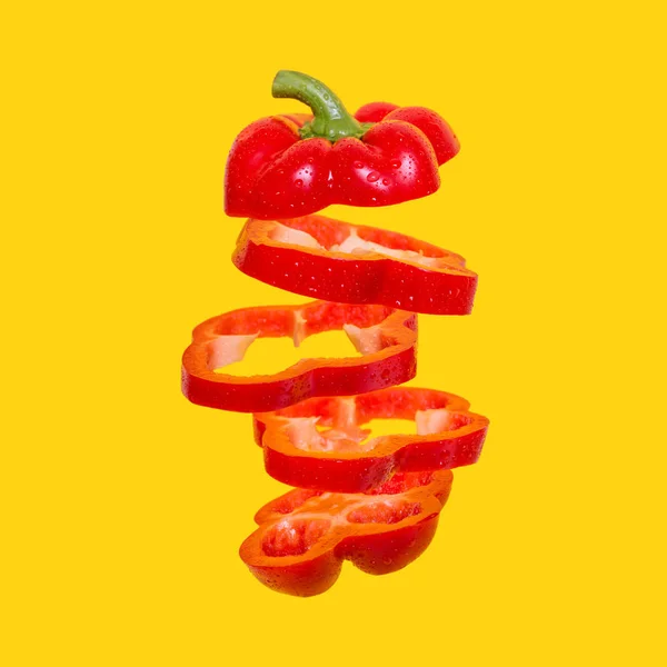 Creatief concept met vliegende rode paprika. Zwevende paprika gesneden op een oranje achtergrond. — Stockfoto