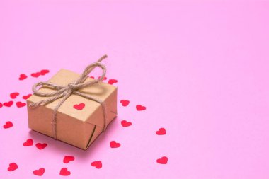 Kraft kağıt pembe bir arka plan üzerinde sarılı bir hediye