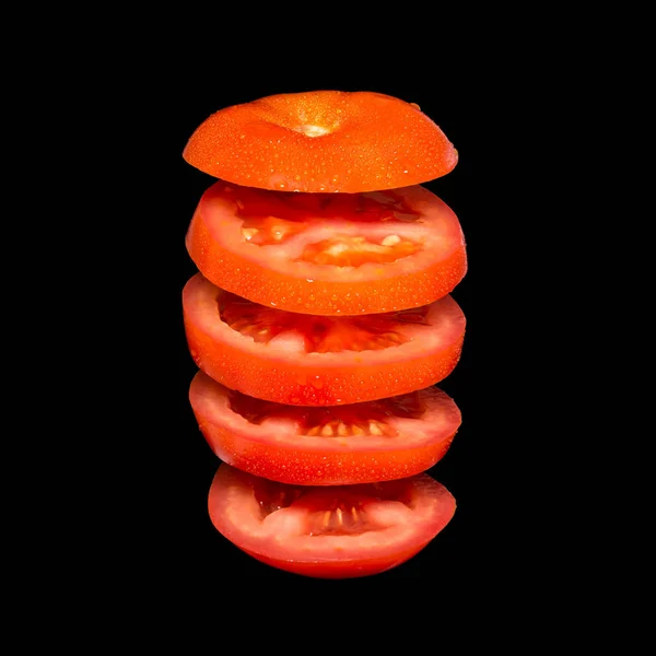 Креативна концепція з літаючим помідором. Нарізаний червоний помідор ізольований на чорному тлі — стокове фото