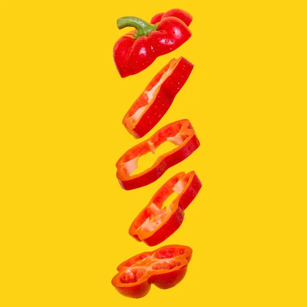 Creatief concept met vliegende rode paprika. Zwevende paprika gesneden op een oranje achtergrond — Stockfoto