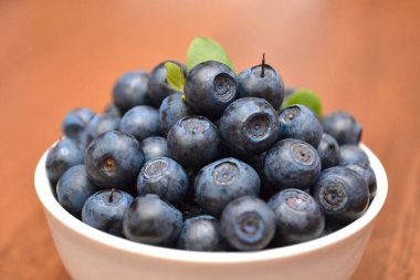 Böğürtlenli beyaz plaka üzerinde bulanık ahşap masa