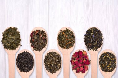Tahta kaşıklar farklı kuru bitkisel çayların beyaz bir ahşap arka plan ayarla