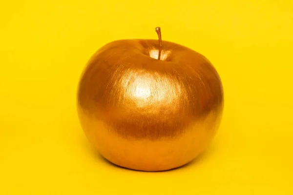 Gold apple on yellow background. Creative concept with fruit. — Stock Photo, Image