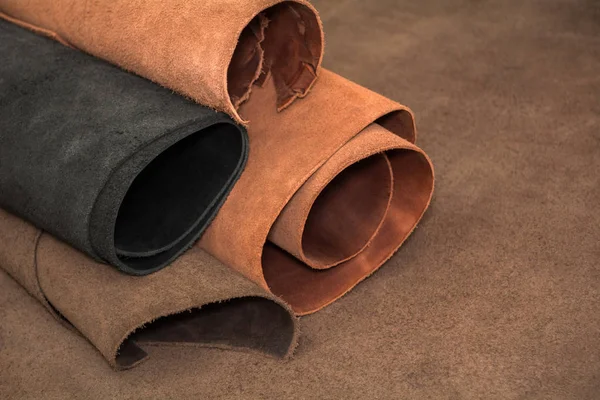 Rullar med naturligt brunt och svart läder. Material för läder hantverk — Stockfoto