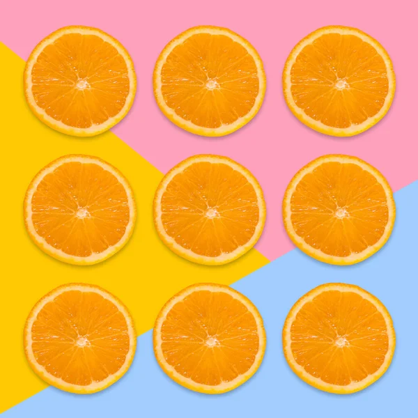 Een stukken van Oranje op een roze, gele en blauwe achtergrond. Van bovenaf bekijken — Stockfoto