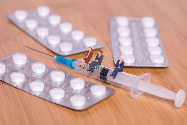 Miniatyr människor, en medicinsk spruta och tabletter. Kreativa begreppet hälso-och sjukvård — Stockfoto