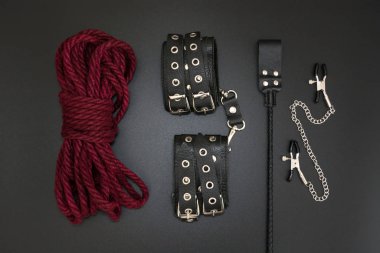 Deri kelepçeler, şibari ipi, meme ucu kıskaçları ve siyah arka planda bdsm oyunları için deste. Yetişkinlerin cinsel oyunları için aksesuarlar