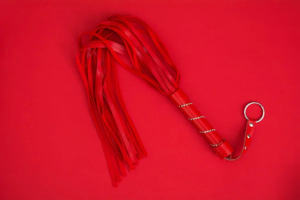 Red whip on red silk background. Accessories for adult sexual games. Toys for BDSM — Stock Photo, Image
