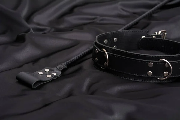 Pila para juegos BDSM y collar de cuero sobre fondo de seda negro — Foto de Stock