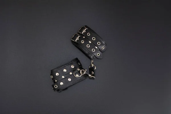 Siyah arka planda deri kelepçeler. Yetişkinlerin cinsel oyunları için aksesuarlar. Bdsm kıyafeti