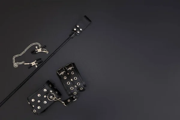 Deri kelepçeler, meme ucu kıskaçları ve siyah arka planda Bdsm oyunları için istifleme. Yetişkinlerin cinsel oyunları için aksesuarlar