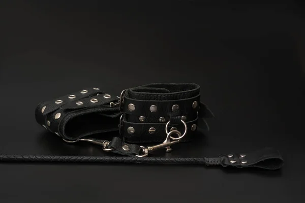 Deri kelepçeler ve siyah arka planda bdsm oyunları için deste. Yetişkinlerin cinsel oyunları için aksesuarlar