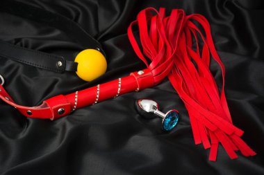 Siyah ipek arka planda kırmızı kırbaç, ağız tıkacı, anal tıpa