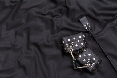 Leather handcuffs and stack on black background. Accessories for adult sexual game. BDSM outfit. clipart