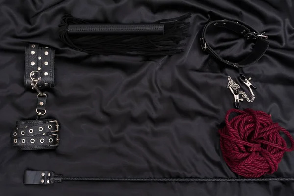 采购产品皮革手铐 钢丝绳 乳头钳 锁链衣领和堆栈在黑色的背景 成人性爱游戏的配件 Bdsm服装 — 图库照片
