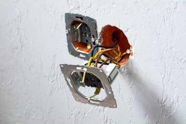 Soket prizi kurulumu. Parçalanmış elektrik prizi, patlayıcı duvarda çıplak kablolar ve özel işaretlerle..