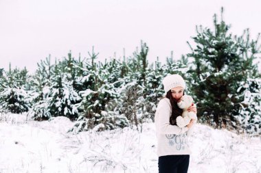 Küçük kız karlı bir kış ormanında yürüyor ve eğleniyor.