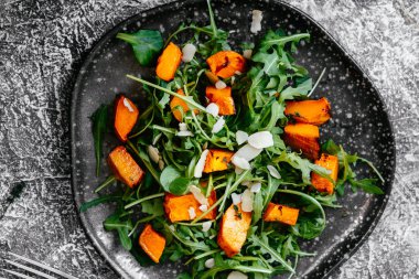 Pişmiş balkabağı vejetaryen salatası, roka ve kuruyemiş.