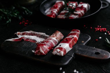 Izgara için baharatlı domuz pastırmalı rulo et.