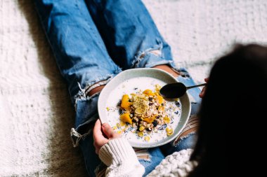 Beyaz kedi, bir kızın elindeki tabaktan muz ve chia tohumlarıyla müsli yiyor.