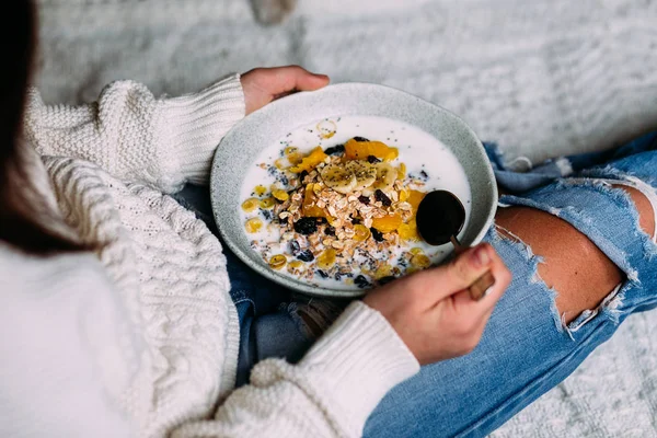 Beyaz kedi, bir kızın elindeki tabaktan muz ve chia tohumlarıyla müsli yiyor.
