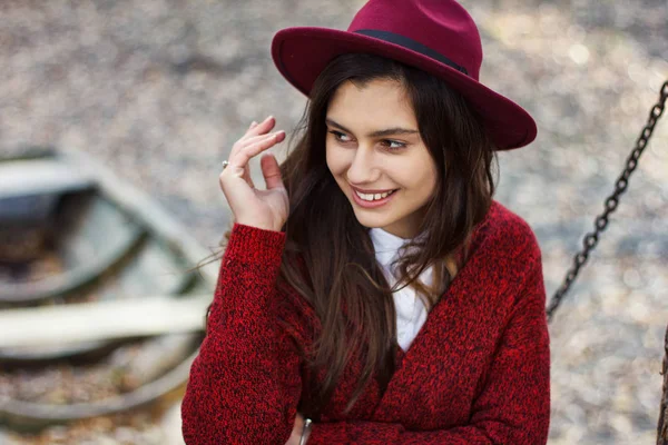 Nettes Mädchen in roter Strickjacke und Hut im Herbst — Stockfoto