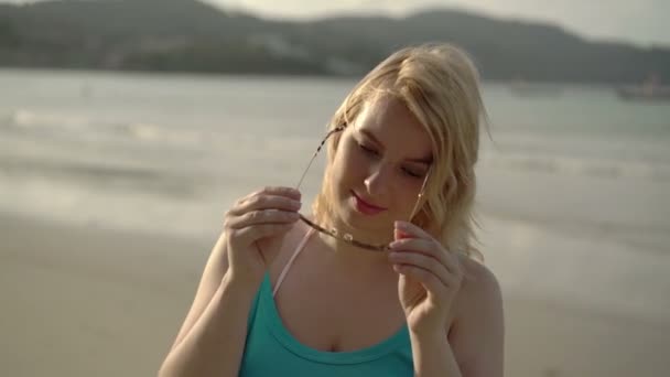 Jeune femme blonde sur la plage portant des lunettes de soleil — Video