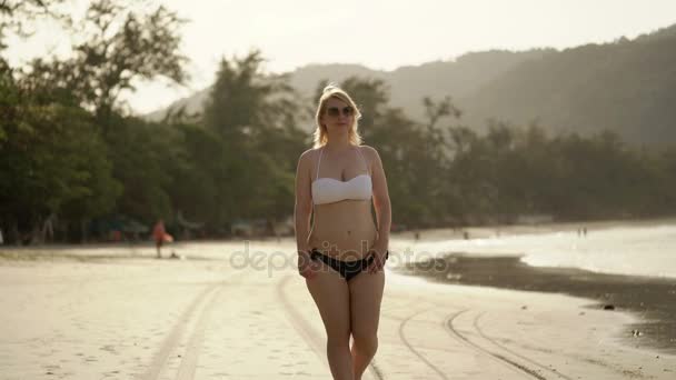 Νεαρή ξανθιά γυναίκα περπάτημα στο μπικίνι στην παραλία — Αρχείο Βίντεο